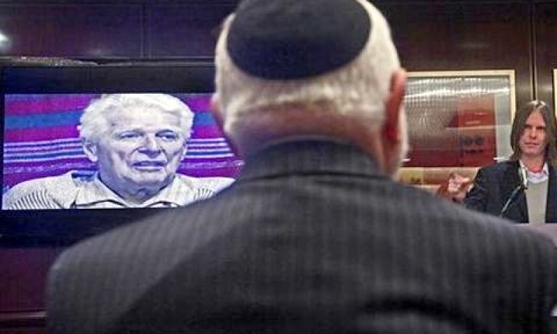 ניצול השואה ליאו זיסמן (80) מאזין להרצאתו של המומחה מארק גולד. על המסך: ברנהרד פרנק [צילום: AP]