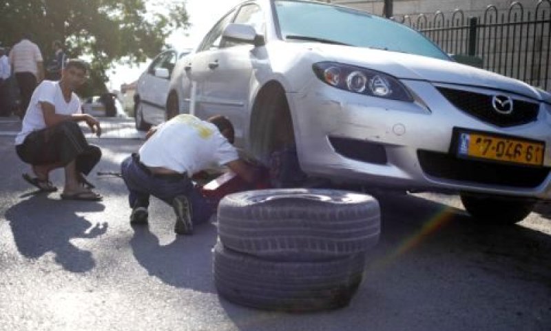 תושבים בוחנים רכב שצמיגיו נוקרו [צילום: פלאש 90]