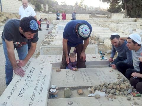 משה לפיד (משמאל) על קבר אביו ואחיו ביום השנה להרצחם [צילום: באדיבות המשפחה]