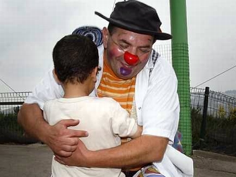 רגע של הפוגה. ליצן אוחז ילד בשדרות [צילום: פלאש 90]