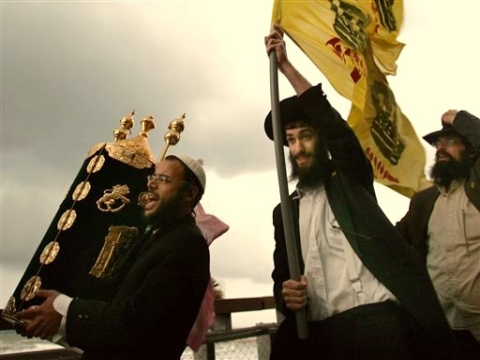 קומץ חבדניקים משיחיסטים נושאים ספר תורה בגשם
