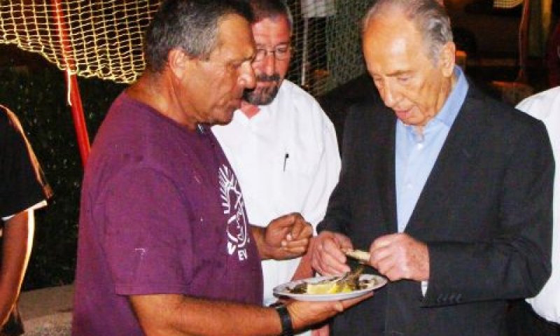 נשיא המדינה טועם סרדינים שהכין מנחם לב הדייג בנמל עין גב [צילום: אריאל צור]