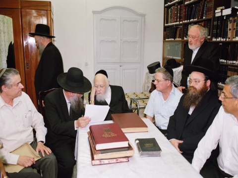 הרב יוסף שלום אלישיב עם הרב אריה דביר ומנכ"ל בנק הפועלים בבדיקת ההיתר עסקה לקראת החתימה. בשולחן יושבים עוד ראש עיריית בני ברק יששכר פרנקהנטל, ציון קינן, מ"מ מנכ"ל בנק הפועלים, אלדד כהנא, היועץ המשפטי של הבנק. עומד מימין: הפרסומאי בני גל.