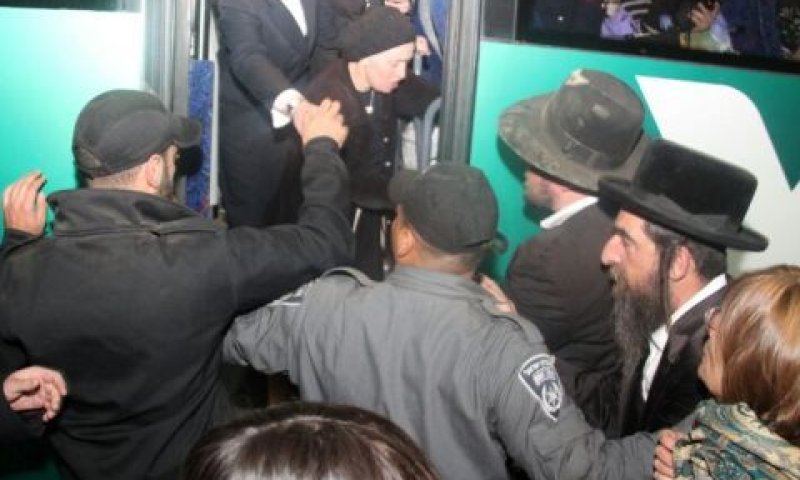 שוטר מנסה לוות לחץ בכניסה לאוטובוס [צילום: האתר החרדי כיכר השבת]
