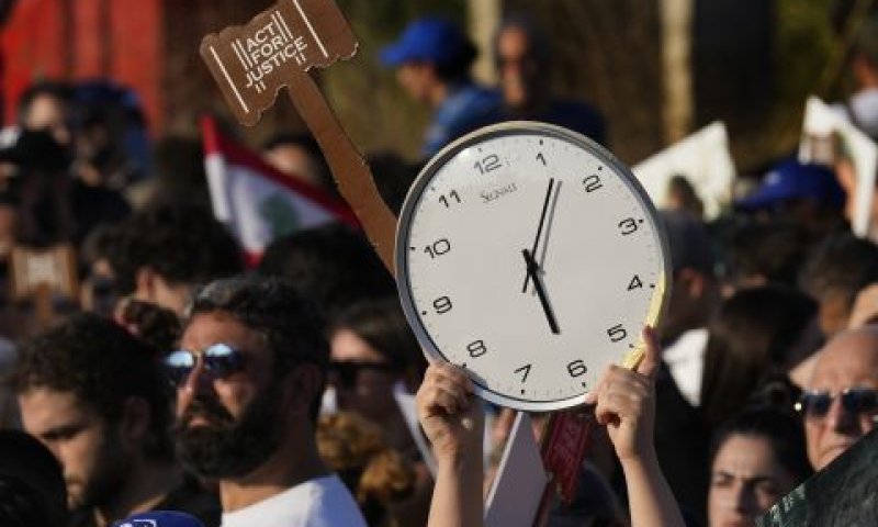 קרובי משפחה של קורבנות הפיצוץ הקטלני בנמל ביירות ב-2020, מחזיקים שעון קיר המראה את שעת הפיצוץ [צילום: חוסיין מלא/AP]
