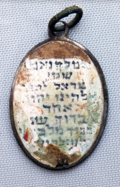 תליון שהתגלה בקבר ההמונים. "אל מלך נאמן שמע ישראל ה אלוהינו ה' אחד ברוך שם כבוד מלכותו לעולם ועד" [צילום: יורם חיימי, רשות העתיקות]