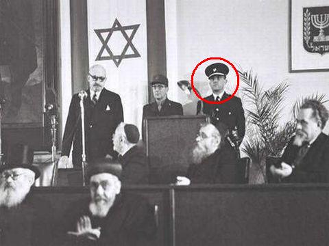 פרופ' חיים ויצמן נושא דברים (17.2.1949) מעל בימת הכנסת לאחר טקס הכתרתו לנשיא המדינה הראשון של מדינת ישראל. עומדים למעלה מימין מפכ"ל המשטרה יחזקאל סהר ולידו האלוף דוד שאלתיאל. יושב בשורה העליונה משמאל, יו"ר הכנסת יוסף שפרינצק. יושבים ליד השולחן בשורה השנייה מימין לשמאל: שר הפנים יצחק גרינבוים, שר הסעד הרב יצחק מאיר לוין ושר הדתות ונפגעי מלחמה הרב יהודה לייב הכהן מימון. יושבים למטה מימין לשמאל: הראשון לציון הרב ציון מאיר חי עוזיאל והרב האשכנזי הראשי יצחק הלוי הרצוג [צילום: לע"מ]