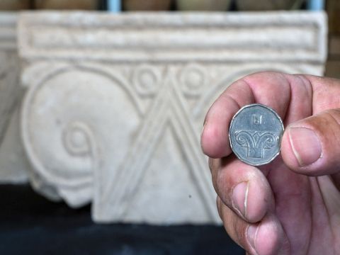 מטבע חמישה שקלים על רקע הכותרת שנחשפה [ צילום: יניב ברמן, רשות העתיקות]