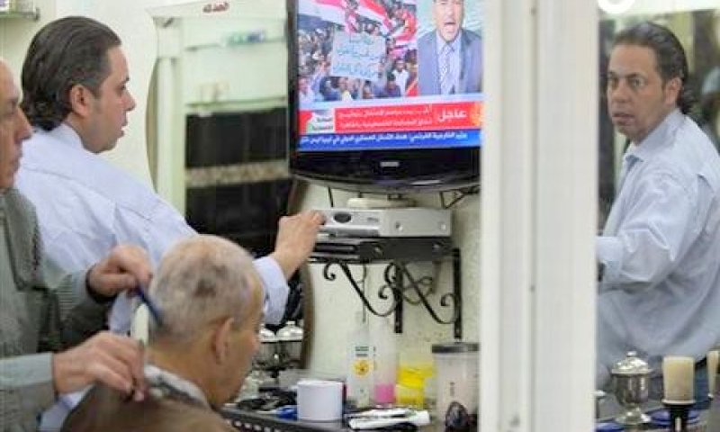 במספרה בירושלים העתיקה צופים באל-ג'זירה בטקס חתימת הסכם הפיוס הפלשתיני בקהיר [צילום: AP]