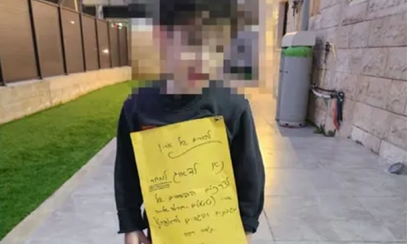 ארי, ילד עם צרכים מיוחדים, עם השלט שהודק לחולצתו [צילום: לפי סעיף 27א' לחוק זכויות יוצרים]