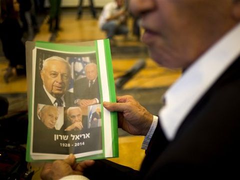 אדם בת"א מחזיק תיקייה ובה תמונות שרון [צילום: AP]