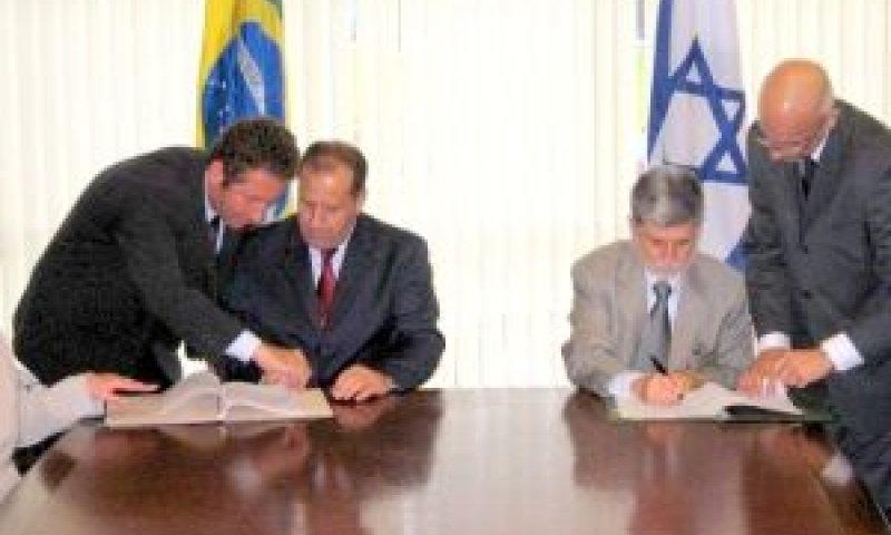 מגלי והבה (משמאל) חותם על ההסכם