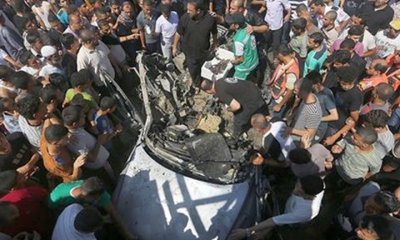 פלשתינים סביב שרידי המכונית שהותקפה [צילום: AP]