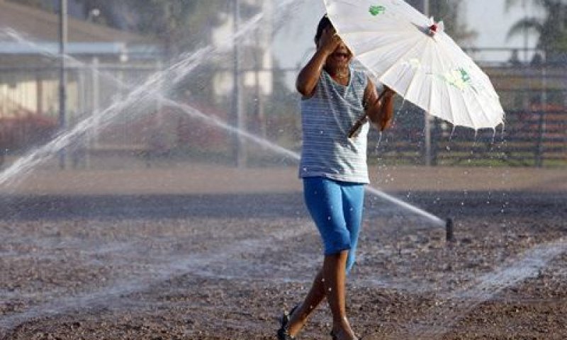 ילדה מאזור לוס אנג'לס משחקת בין הממטרות כדי להימלט מהחום המעיק, היום [צילום: AP]