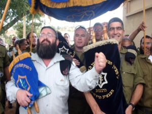 [תהלוכת הכנסת ספרי התורה לבית הכנסת. משמאל רב פקמ"ז יהודה ויזנר]