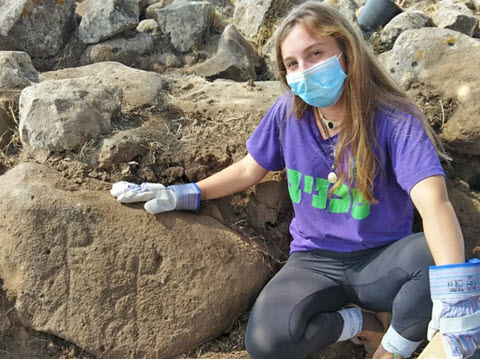 עפרי איתן, חניכה במכינת כפר הנשיא שהשתתפה בחפירות, עם האבן החרותה [צילום: תדהר מואב, רשות העתיקות]