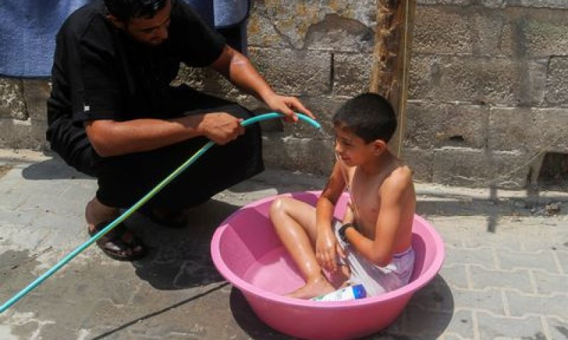 ילד מצטנן בגיגית מים בעזה [צילום: עבד רחים חטיב/פלאש 90]