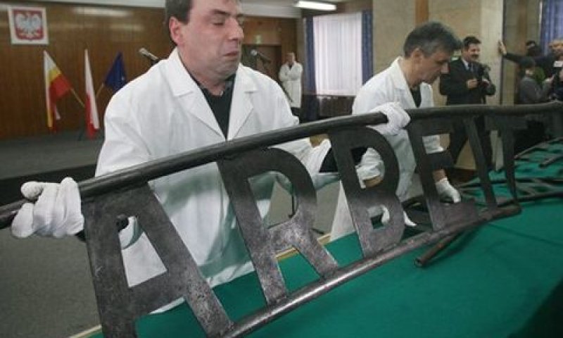 מומחים מטעם המשטרה בודקים את השלט לפני העברתו לאתר ההנצחה באושוויץ [צילום: AP]