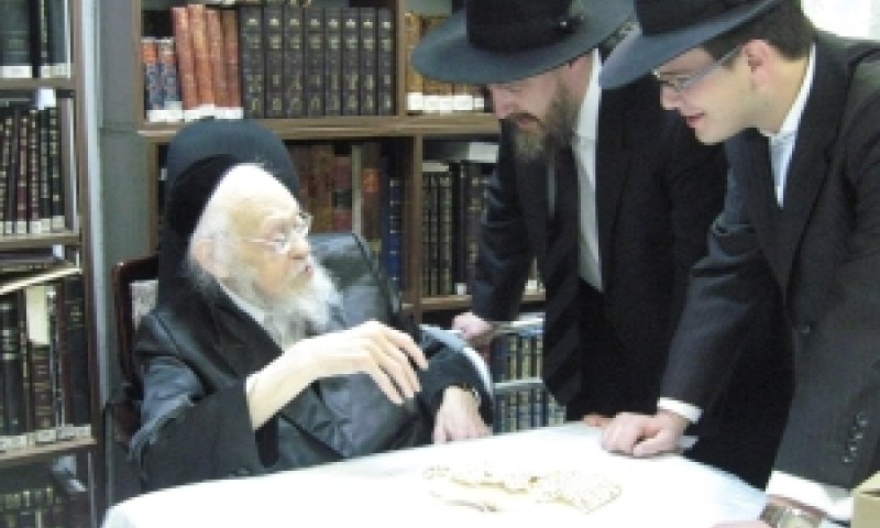 הרב אלישיב מקבל את הרב קוק ובנו. בשולחן לפניו מונחות מצות