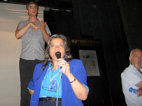 תושבת שהוזמנה לבמה לדבר. על הבמה: מתרגם לשפת הסימנים