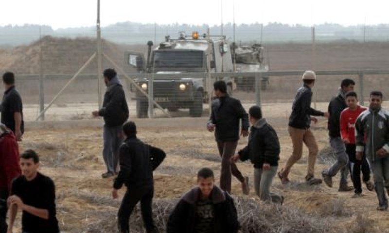 פלשתינים ברצועת עזה מתגרים בחיילי צה"ל ליד גדר המערכת ביום שישי [צילום: AP]