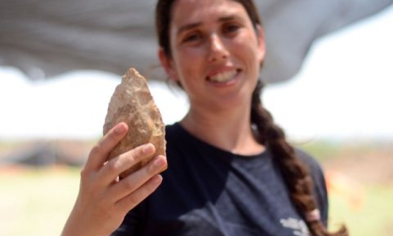 מעין שמר, מנהלת החפירה מטעם רשות העתיקות, מציגה אבן יד בת חצי מליון שנה [צילום: רשות העתיקות]