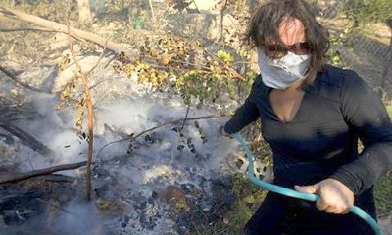 אישה מכבה אש בפתח ביתה בעין הוד [צילום: AP]