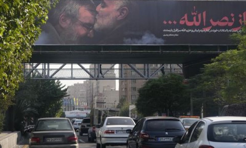 כלי רכב חולפים על פני שלט חוצות בטהרן המציג את גנרל משמרות המהפכה קאסם סולימאני, שנהרג ב-2020 בעירק, מנשק את מצחו של נסראללה [צילום: ואחיד סלמי/AP]