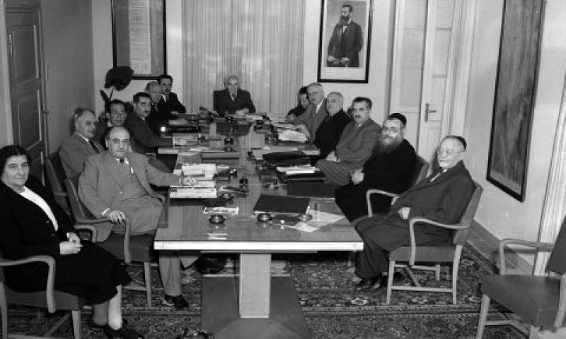 מימין לשמאל: יהודה לייב מימון, יצחק מאיר לוין, חיים משה שפירא, דוד רמז, פנחס רוזן, זאב שרף (מזכיר הממשלה), דוד בן גוריון, משה שרת, אליעזר קפלן, דב יוסף, צבי מימון (קצרן הממשלה), בכור-שלום שטרית, זלמן שז"ר, גולדה מאיר [צילום: הוגו מנדלסון/לע"מ]