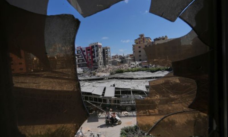 מבנים בצור שנפגעו מתקיפות צה"ל נראים דרך זכוכית מנופצת מבית החולים ג'בל אמל [צילום: חסן עמר/AP]