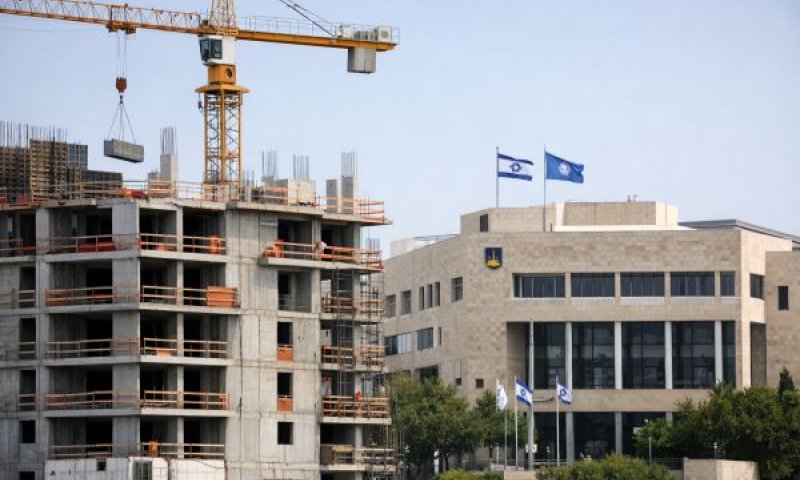 אתר בנייה עם בניין עירוני ברקע [עיבוד AI]